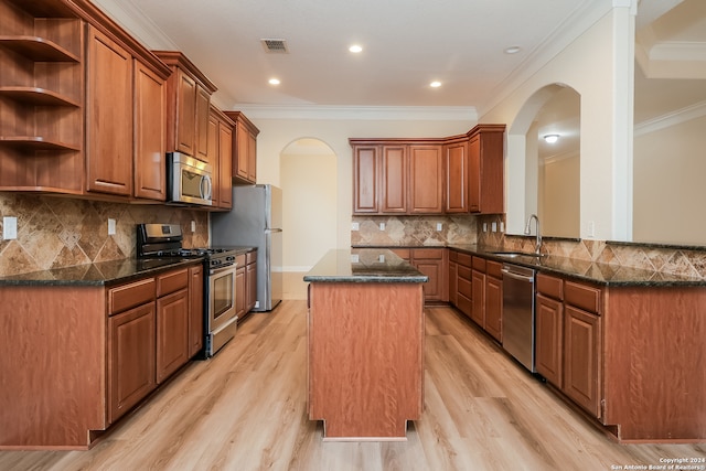 kitchen with ornamental molding, a center island, light wood-type flooring, and appliances with stainless steel finishes