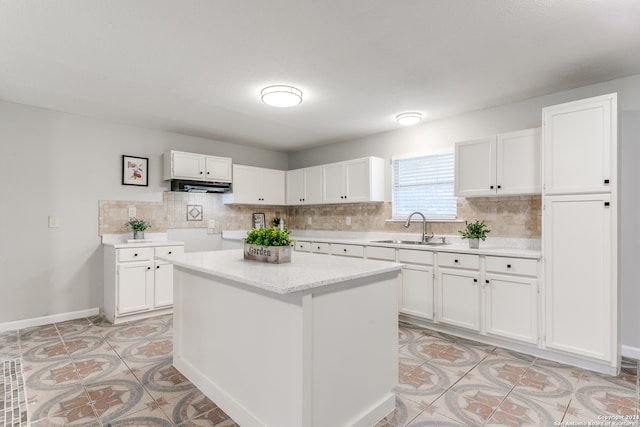 kitchen featuring tasteful backsplash, a kitchen island, sink, light tile patterned floors, and white cabinetry