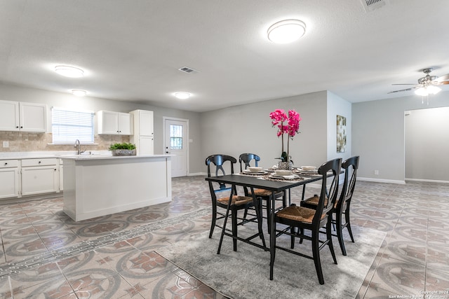 dining room featuring ceiling fan, sink, light tile patterned floors, and a textured ceiling