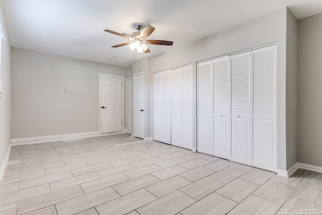 unfurnished bedroom featuring ceiling fan and two closets