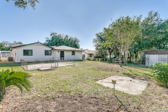 rear view of property with central AC unit, a patio area, and a lawn