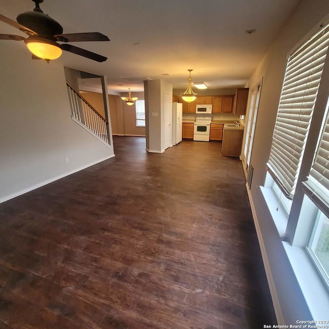 unfurnished living room featuring sink, dark hardwood / wood-style floors, and ceiling fan with notable chandelier