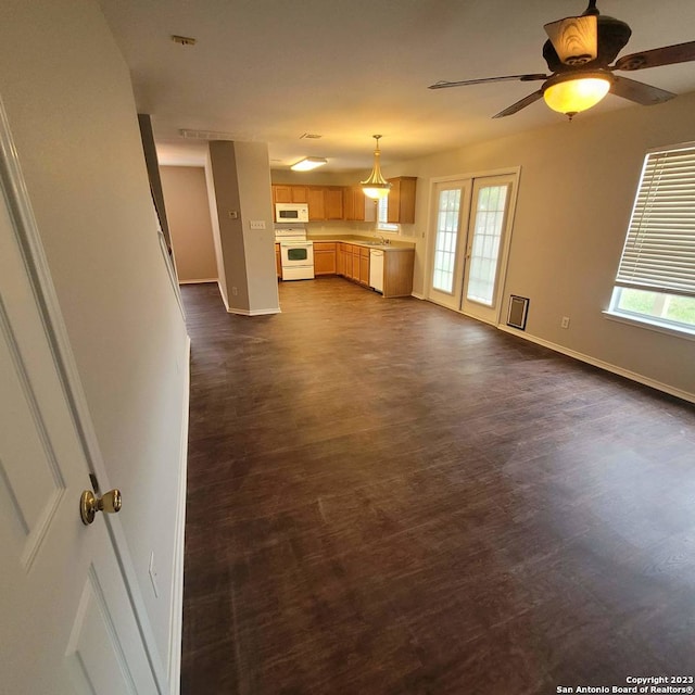 unfurnished living room featuring a wealth of natural light, french doors, ceiling fan, and dark wood-type flooring