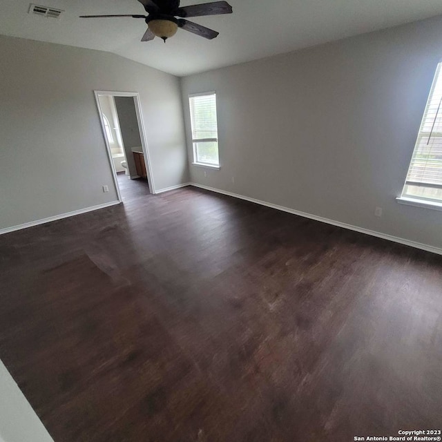 empty room with dark hardwood / wood-style flooring, ceiling fan, plenty of natural light, and lofted ceiling