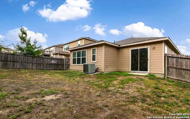 back of property with central AC unit and a lawn