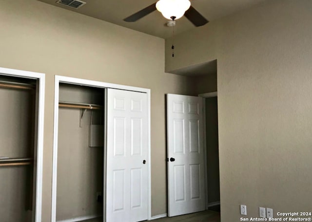 unfurnished bedroom featuring ceiling fan and multiple closets