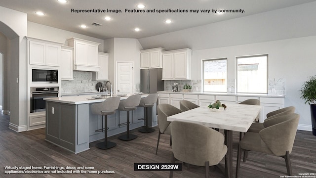 kitchen with a center island with sink, dark hardwood / wood-style floors, white cabinetry, and appliances with stainless steel finishes