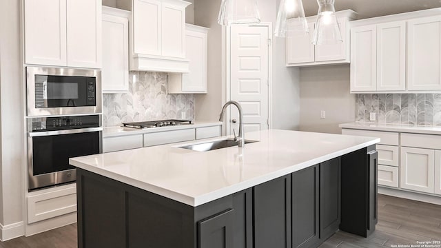 1849 Gyst Rd, Seguin, TX 78155 - kitchen with stainless steel appliances, a sink, white cabinets, backsplash, and a center island with sink