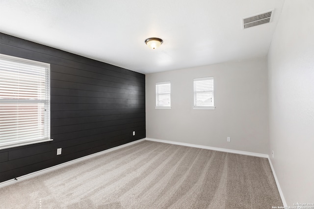 unfurnished room featuring carpet floors and wooden walls