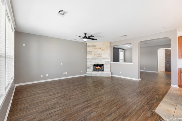 unfurnished living room with a fireplace, ceiling fan, and dark wood-type flooring