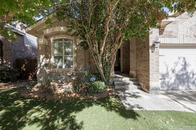 view of property hidden behind natural elements featuring a front lawn and a garage