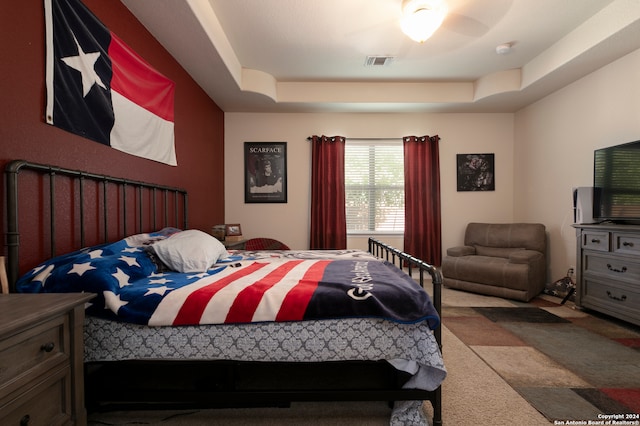 carpeted bedroom with a tray ceiling and ceiling fan