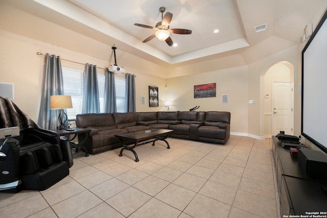 tiled living room with a raised ceiling and ceiling fan