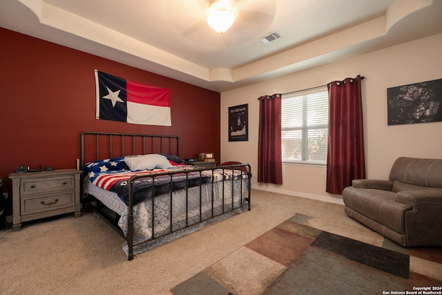 carpeted bedroom with ceiling fan and a raised ceiling