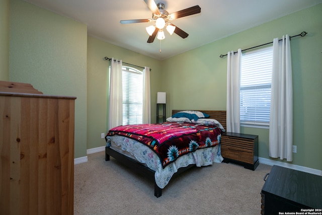 bedroom with multiple windows, ceiling fan, and light carpet