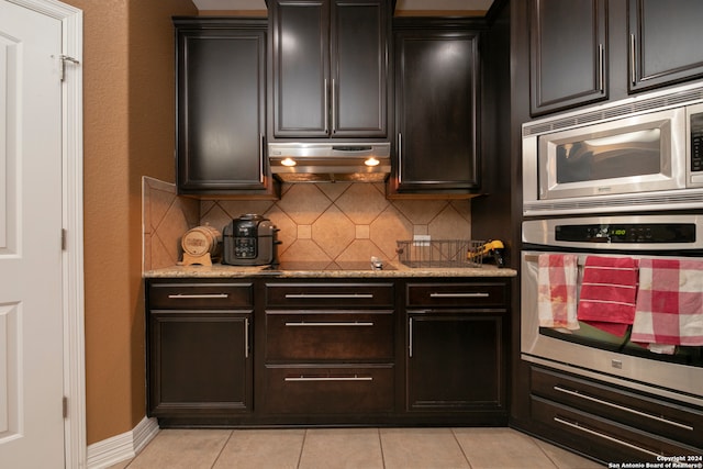 kitchen featuring appliances with stainless steel finishes, tasteful backsplash, light stone counters, dark brown cabinetry, and light tile patterned flooring