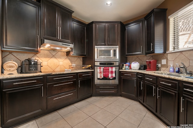 kitchen with tasteful backsplash, sink, light tile patterned floors, and stainless steel appliances