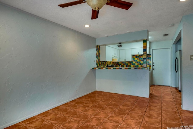 kitchen with white cabinets, ceiling fan, stainless steel fridge, and a textured ceiling