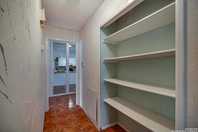 hall featuring tile patterned floors and a textured ceiling