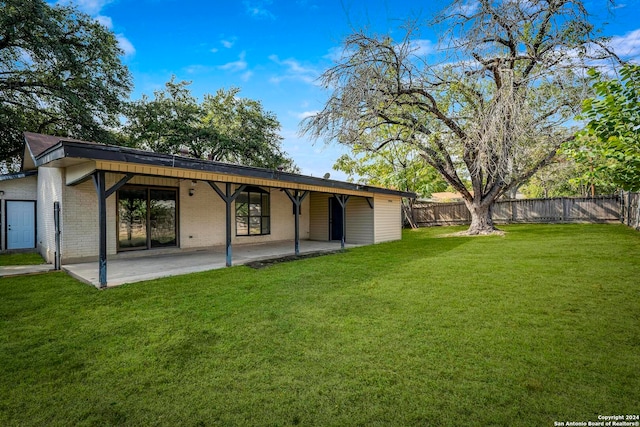 rear view of house featuring a lawn and a patio