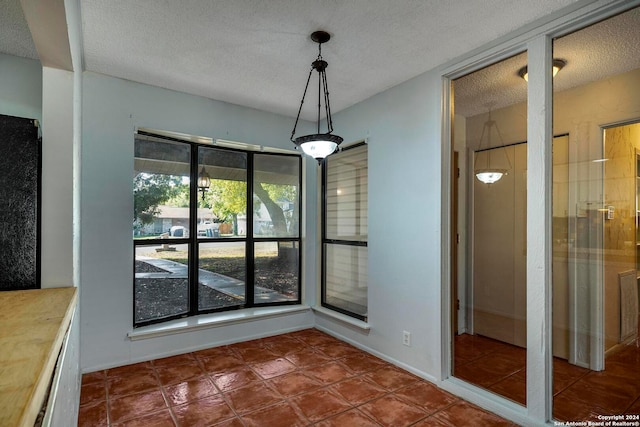 unfurnished dining area featuring dark tile patterned floors and a textured ceiling