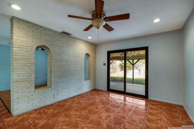 spare room featuring ceiling fan, brick wall, and a textured ceiling