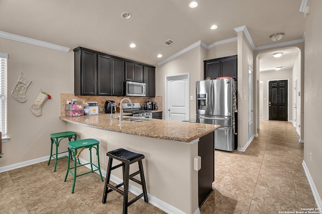 kitchen featuring light stone countertops, stainless steel appliances, tasteful backsplash, kitchen peninsula, and crown molding