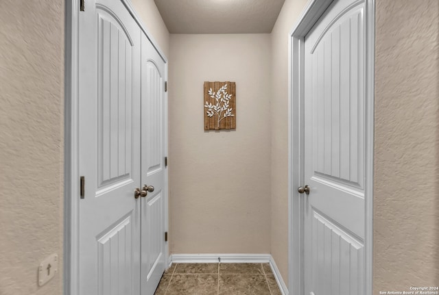 hall featuring a textured ceiling and tile patterned floors