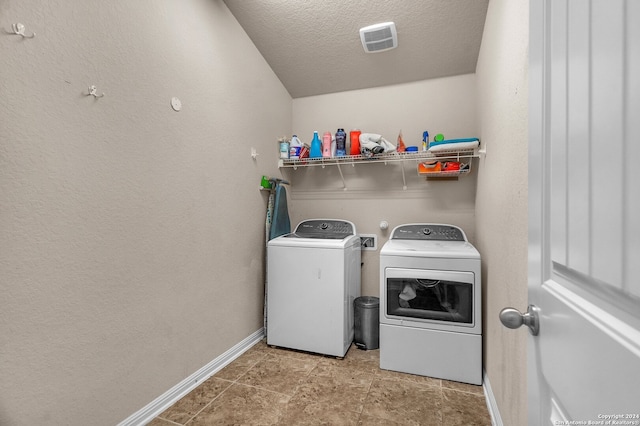 laundry room with a textured ceiling and washing machine and clothes dryer