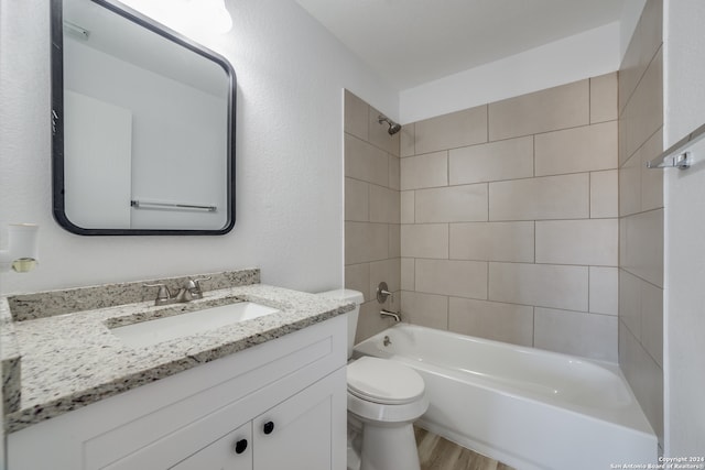 full bathroom featuring vanity, wood-type flooring, tiled shower / bath combo, and toilet