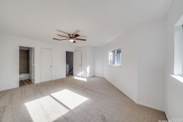 unfurnished bedroom featuring ensuite bath, ceiling fan, light carpet, and lofted ceiling