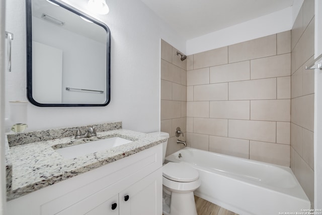 full bathroom featuring vanity, hardwood / wood-style floors, tiled shower / bath combo, and toilet