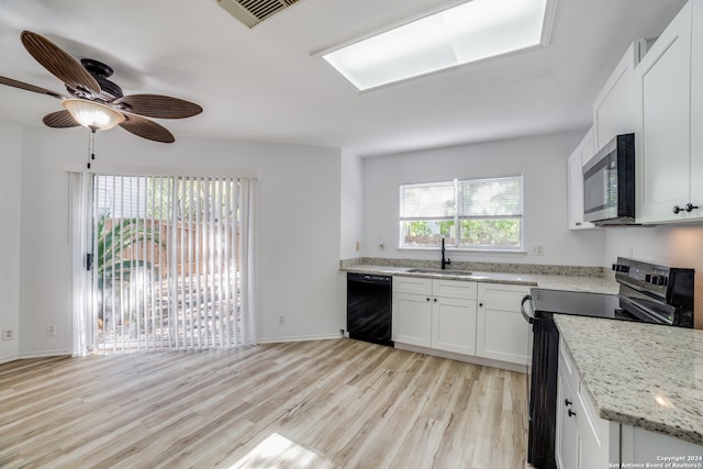 kitchen featuring light stone countertops, white cabinetry, sink, black appliances, and light wood-type flooring