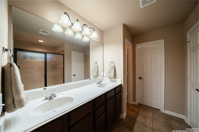 bathroom featuring tile patterned flooring, vanity, a shower with door, and a textured ceiling