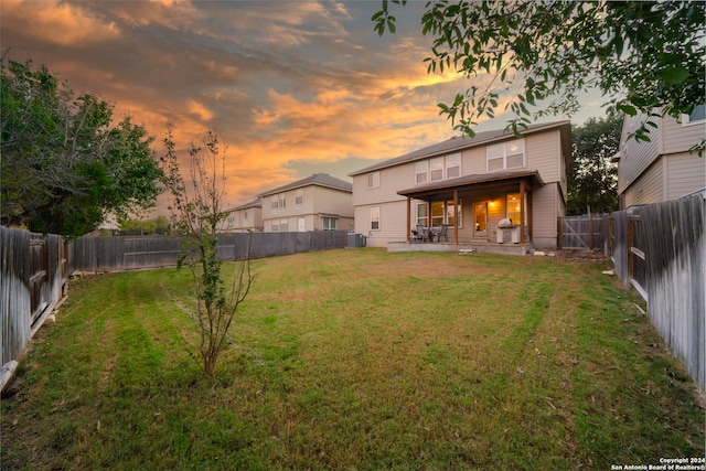 yard at dusk with a patio area and central AC