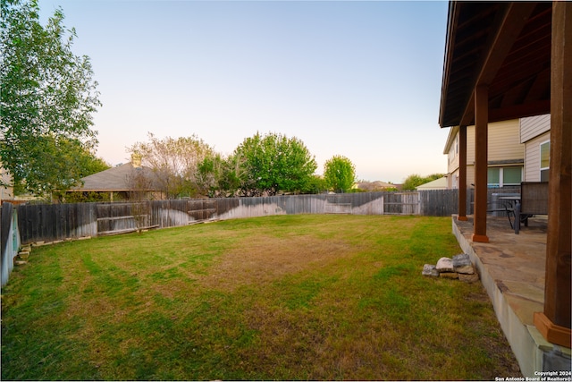 yard at dusk featuring a water view and a patio area