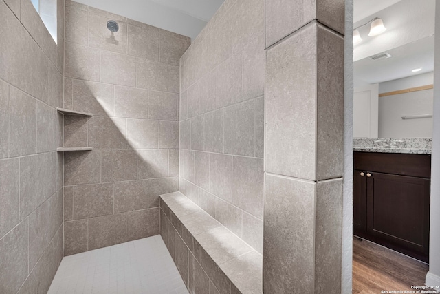 bathroom with hardwood / wood-style floors, vanity, and tiled shower