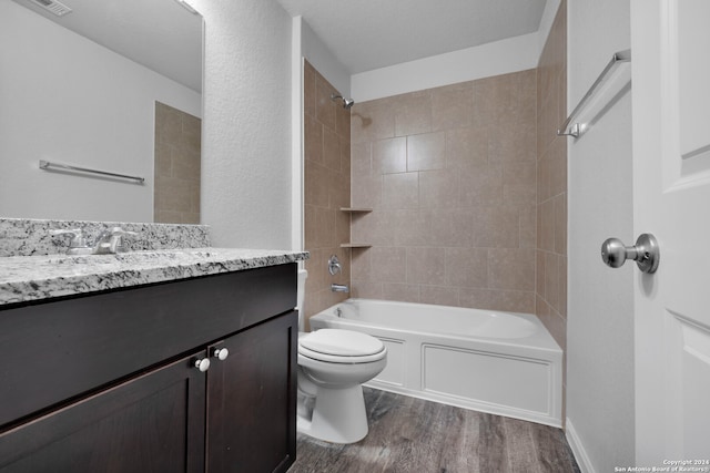 full bathroom featuring hardwood / wood-style flooring, vanity, toilet, and tiled shower / bath