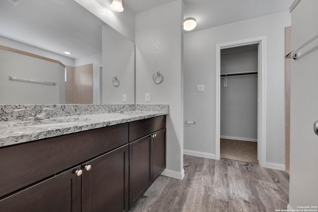 8559 Laxey Wheel, San Antonio, TX 78254 - full bathroom featuring wood finished floors, double vanity, a walk in closet, and baseboards