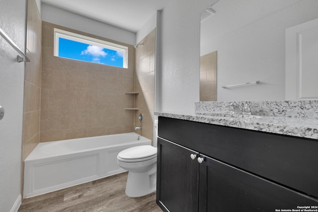 full bathroom featuring vanity, wood-type flooring, tiled shower / bath combo, and toilet