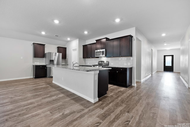 kitchen featuring dark brown cabinetry, stainless steel appliances, a kitchen island with sink, sink, and hardwood / wood-style flooring