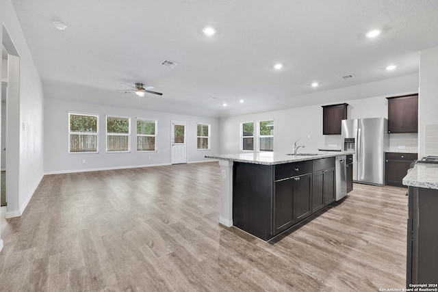 kitchen with light hardwood / wood-style floors, sink, a kitchen island with sink, and appliances with stainless steel finishes