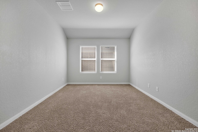 carpeted spare room featuring lofted ceiling