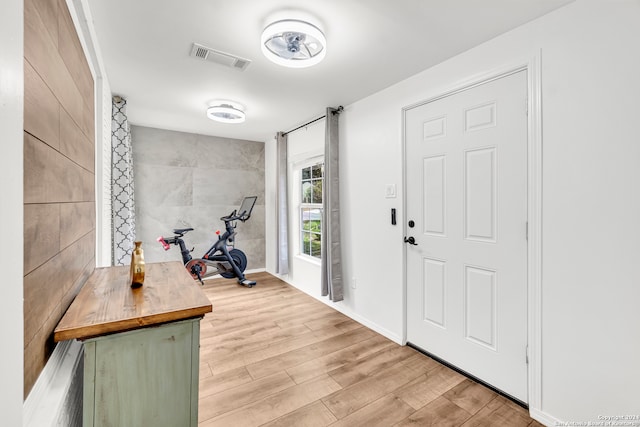 entryway with light wood-type flooring and tile walls