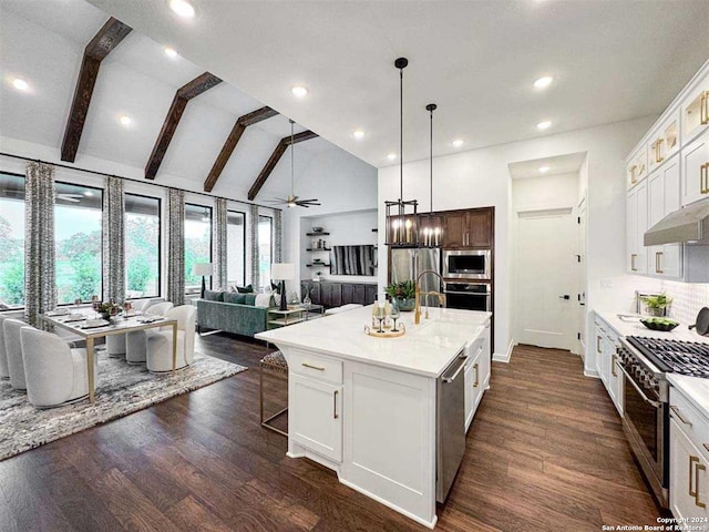 kitchen featuring white cabinets, open floor plan, appliances with stainless steel finishes, a center island with sink, and glass insert cabinets