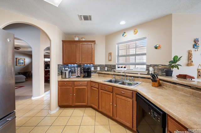 kitchen with black dishwasher, tasteful backsplash, stainless steel refrigerator, and sink