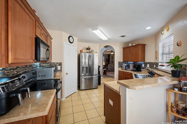 kitchen with kitchen peninsula, tasteful backsplash, a textured ceiling, sink, and black appliances