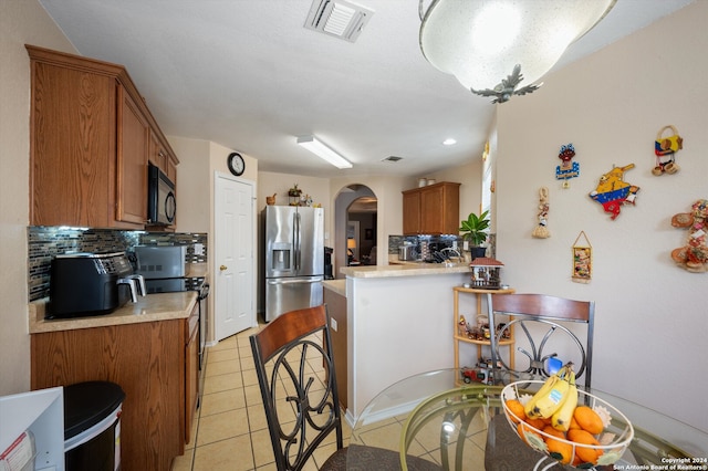 kitchen featuring kitchen peninsula, light tile patterned floors, stainless steel appliances, and tasteful backsplash