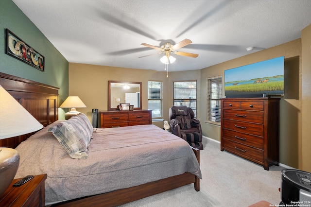 bedroom featuring ceiling fan, light colored carpet, and a textured ceiling