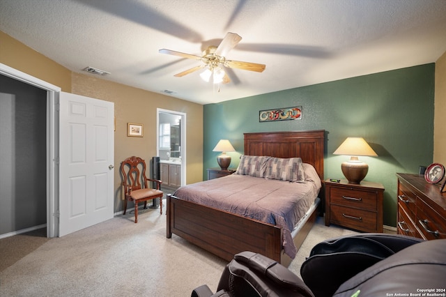 carpeted bedroom with a textured ceiling, connected bathroom, and ceiling fan